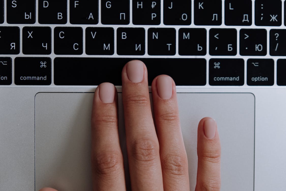 a hand resting on a laptop